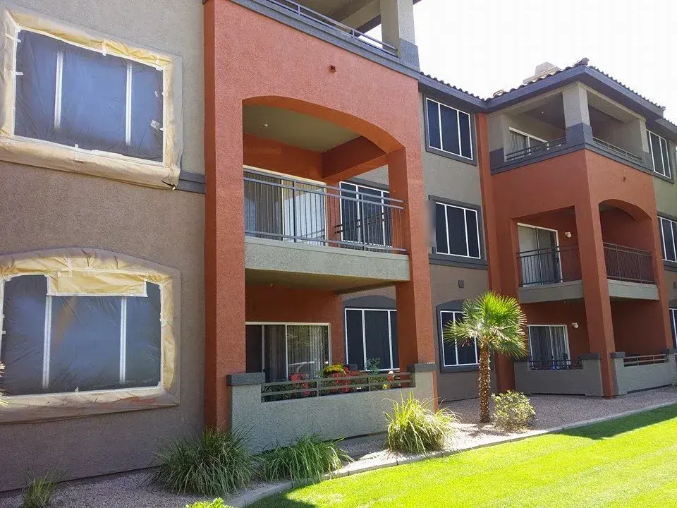 Apartment community repaint in progress, with windows masked and new terracotta and gray colors