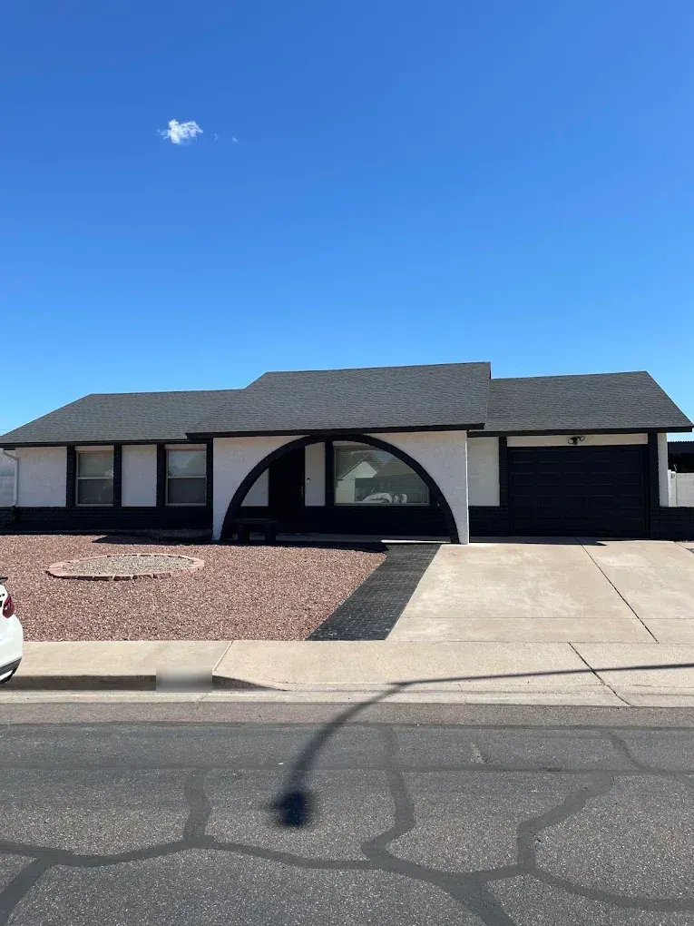 White stucco home with bold black trim, arch and garage door