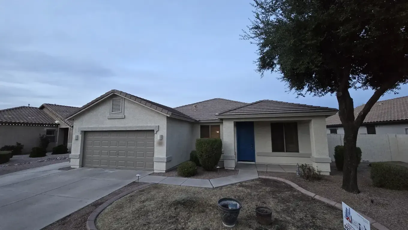 Freshly painted stucco home with a blue front door and an Executive Painting yard sign