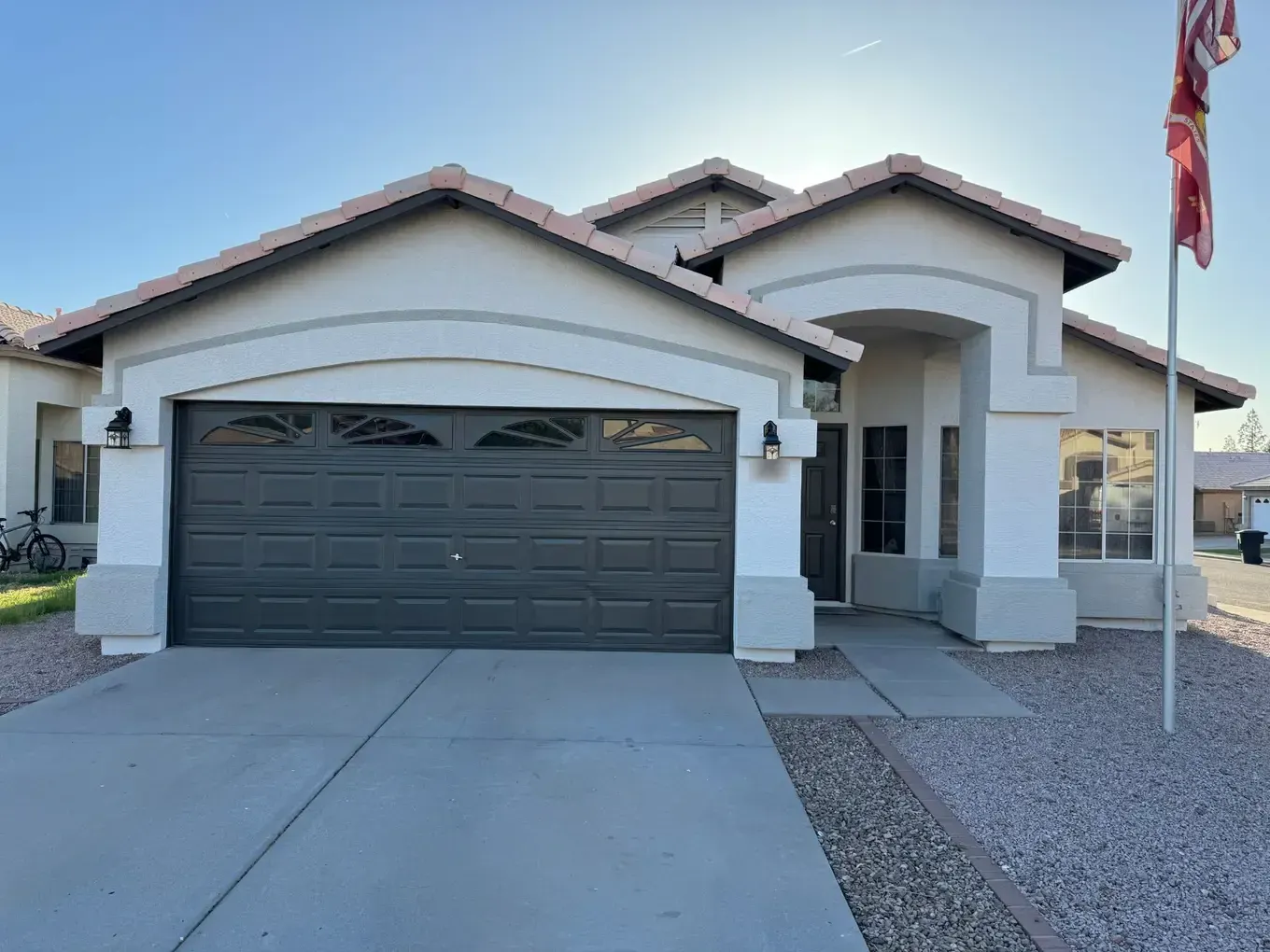 White stucco home with gray accent bands and a dark brown garage door and front door