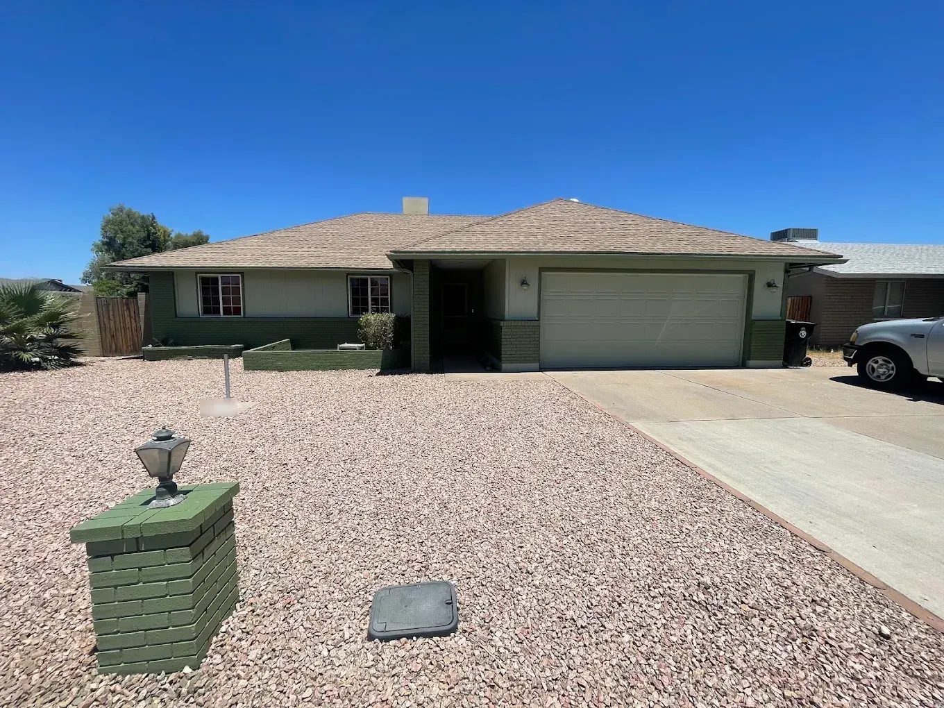 Ranch home with green painted brick, light siding and a matching lamp post