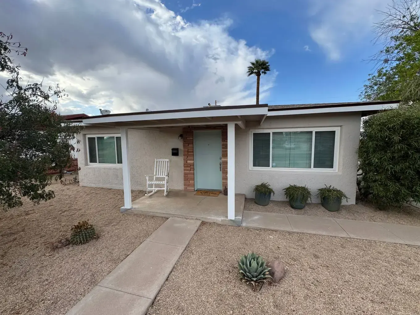 Stucco home with freshly painted white porch posts and fascia and a mint front door