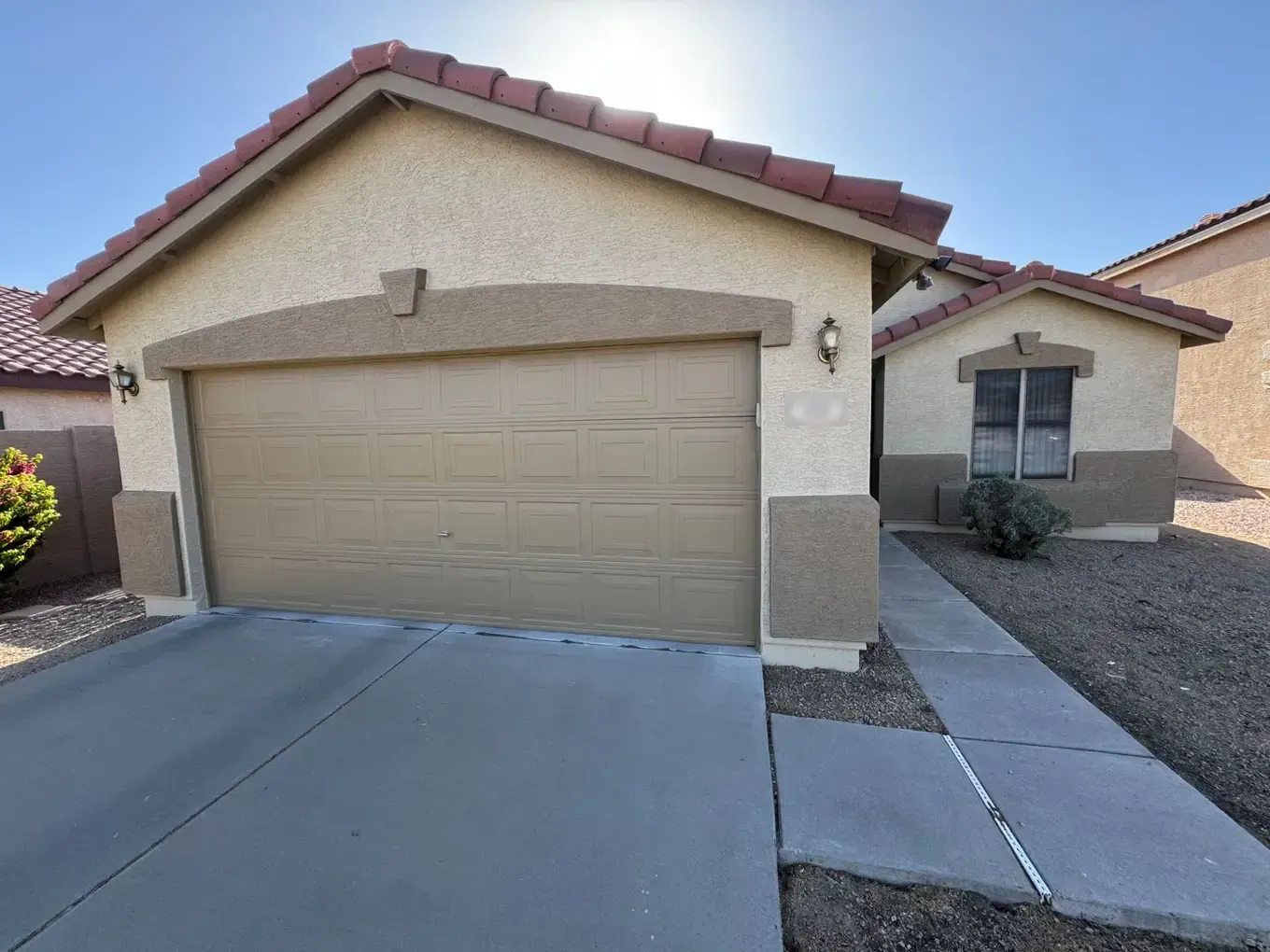 Tan stucco home with darker tan trim, pop-outs and garage door