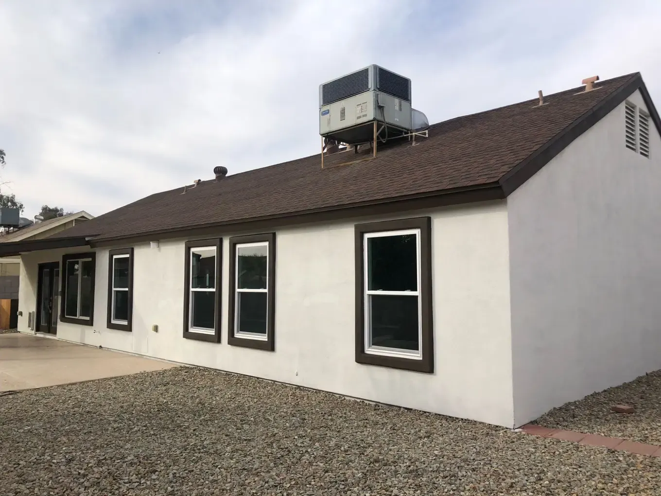 Back of a white stucco home with dark brown trim around new windows