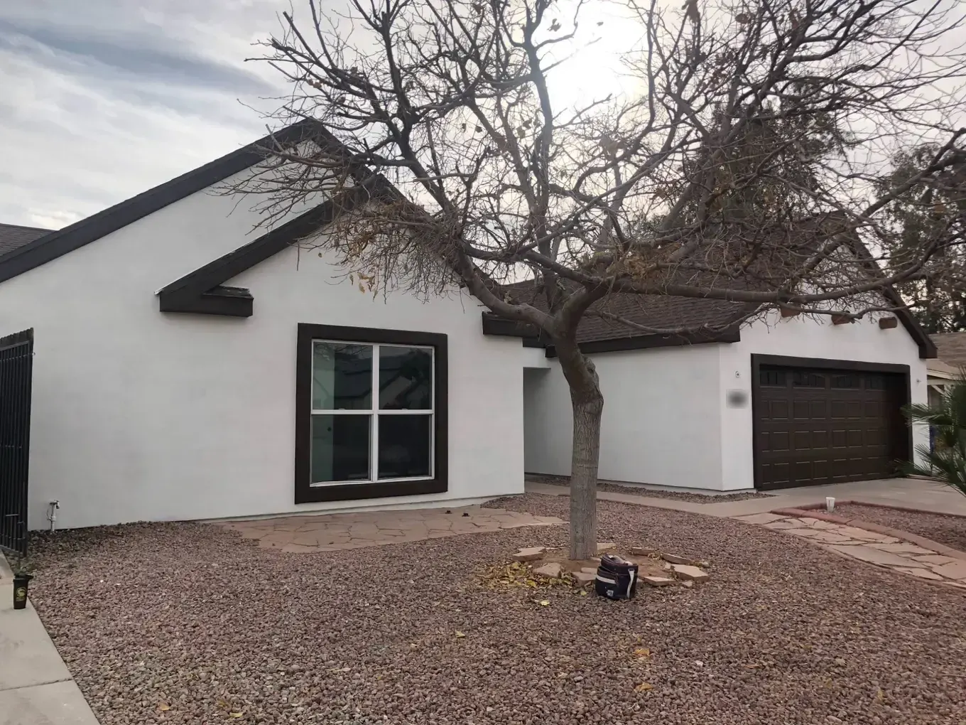 White stucco home with dark brown window trim, fascia and garage door