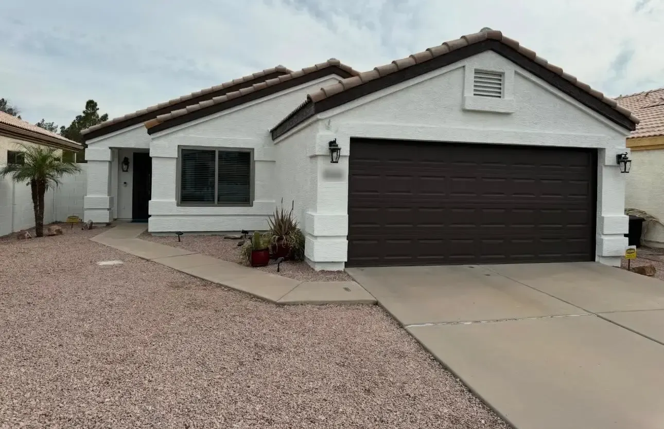 White stucco home with a dark brown garage door, fascia and window trim