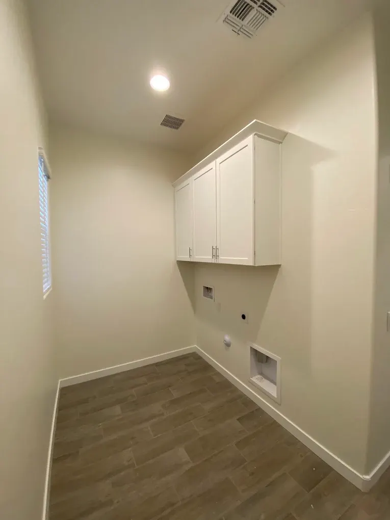 Freshly painted laundry room with white cabinets and baseboards