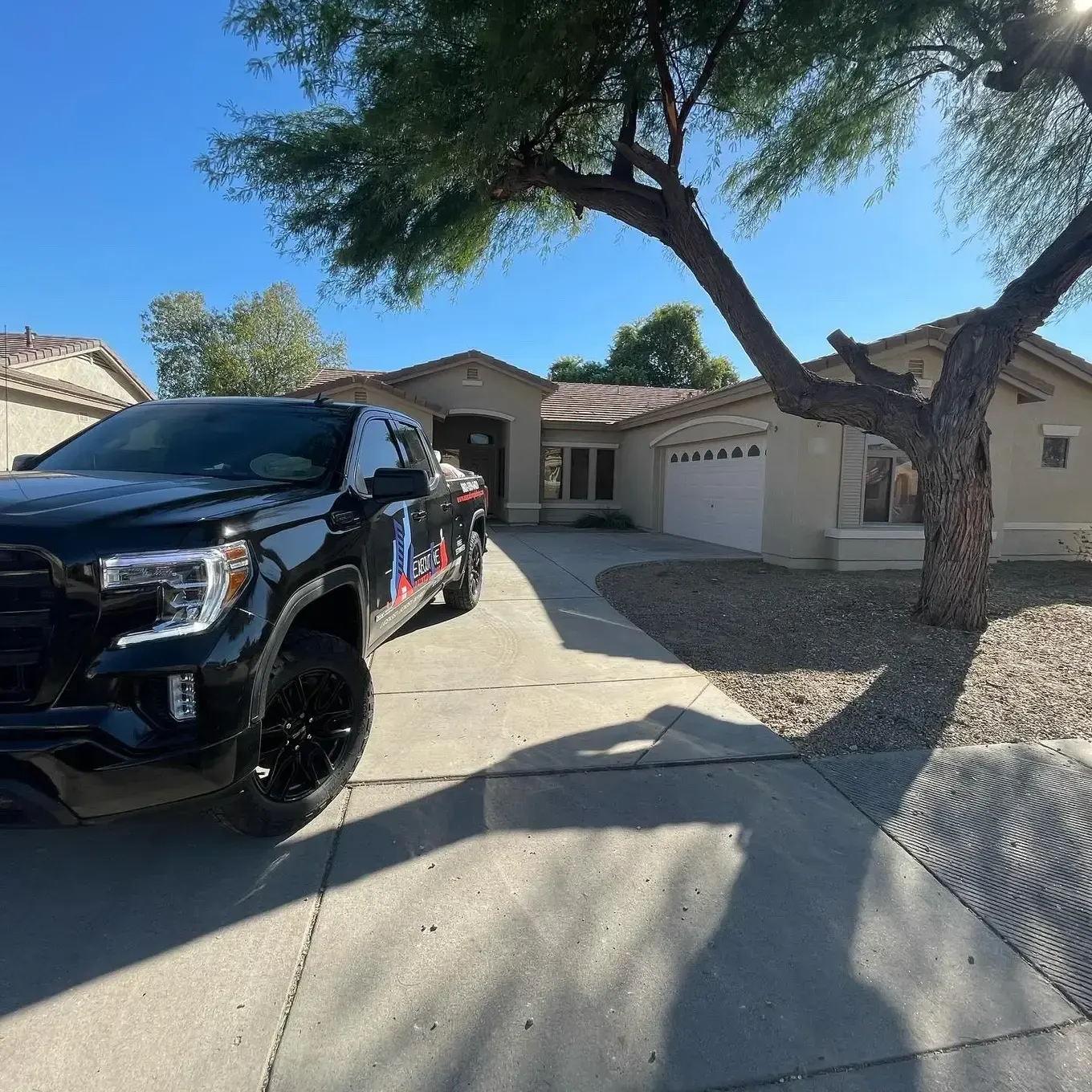 Executive Painting truck parked in the driveway of a freshly painted stucco home
